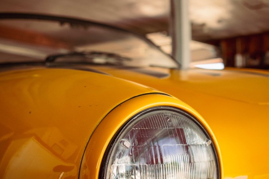 Close-up of a yellow Volkswagen Karmann Ghia headlight in the Motion Imports showroom