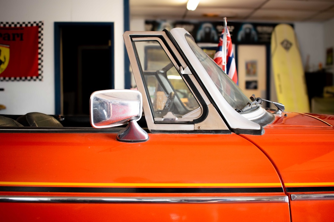 Orange MGB Roadster side profile inside the Motion Imports showroom